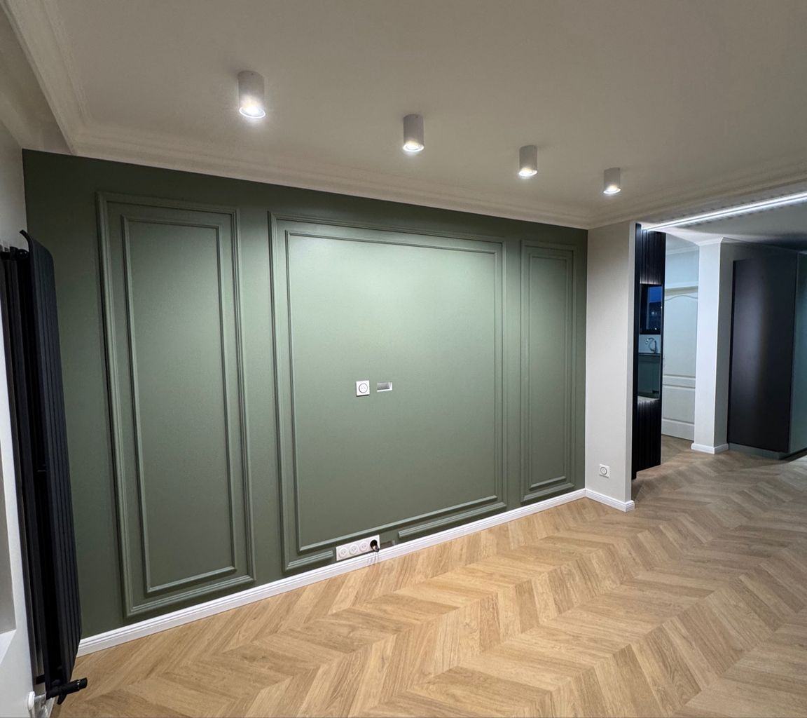 Pièce après travaux : mur vert à boiseries et parquet à chevrons
