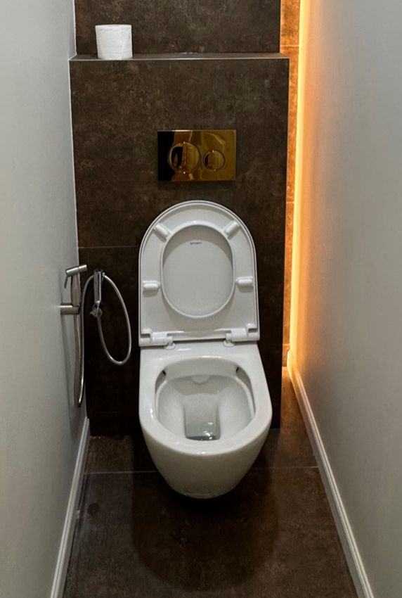 WC après travaux : WC suspendu, mur en carrelage sombre et éclairage LED d'ambiance