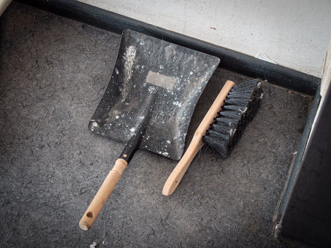 Dustpan and brush on a grey floor after works