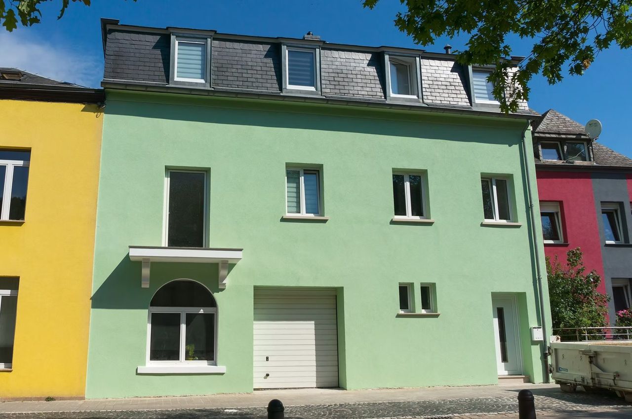 Townhouse with a renovated façade, green render and slate roof