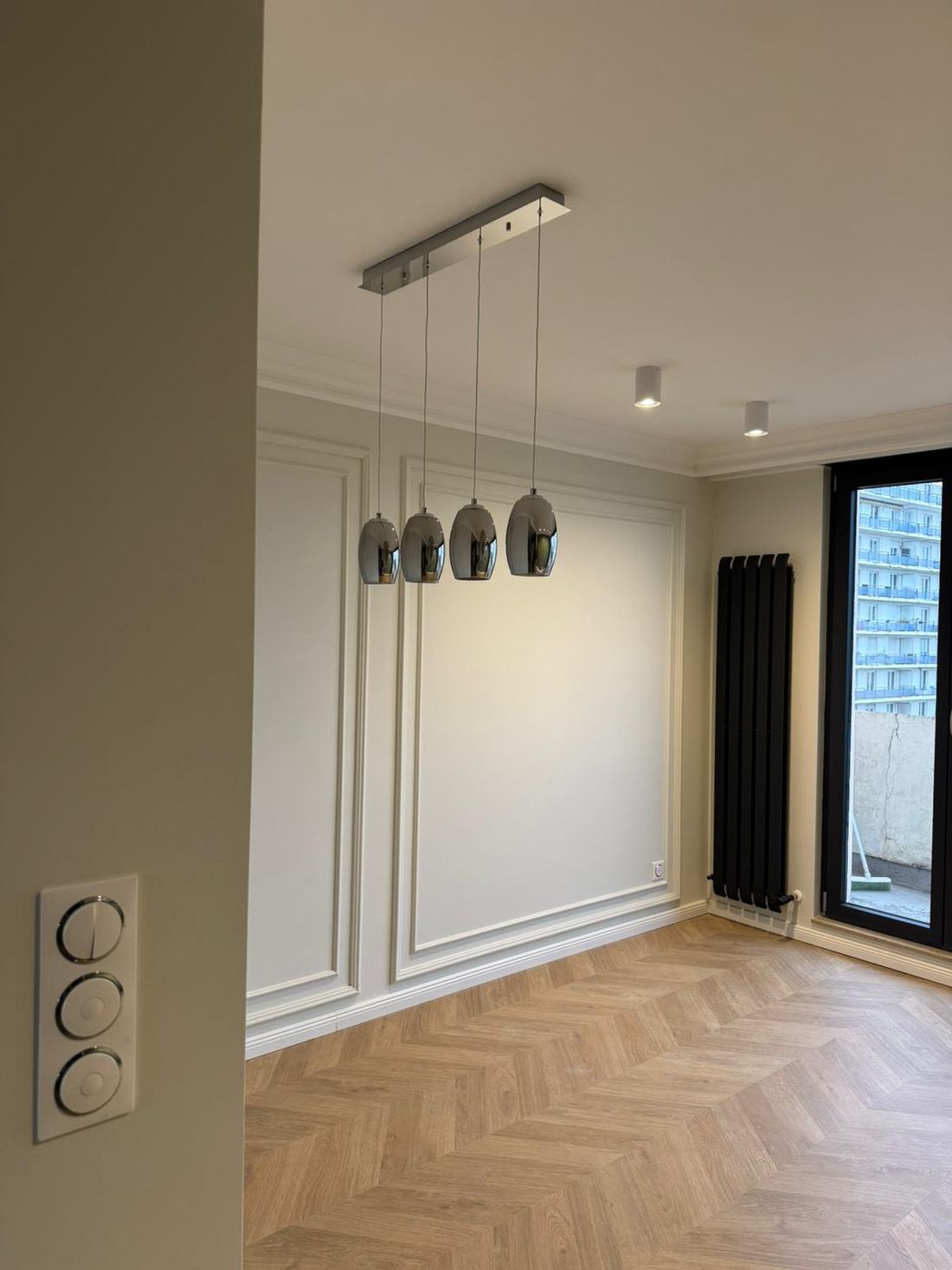 Pièce aux boiseries murales avec suspension design et radiateur vertical noir