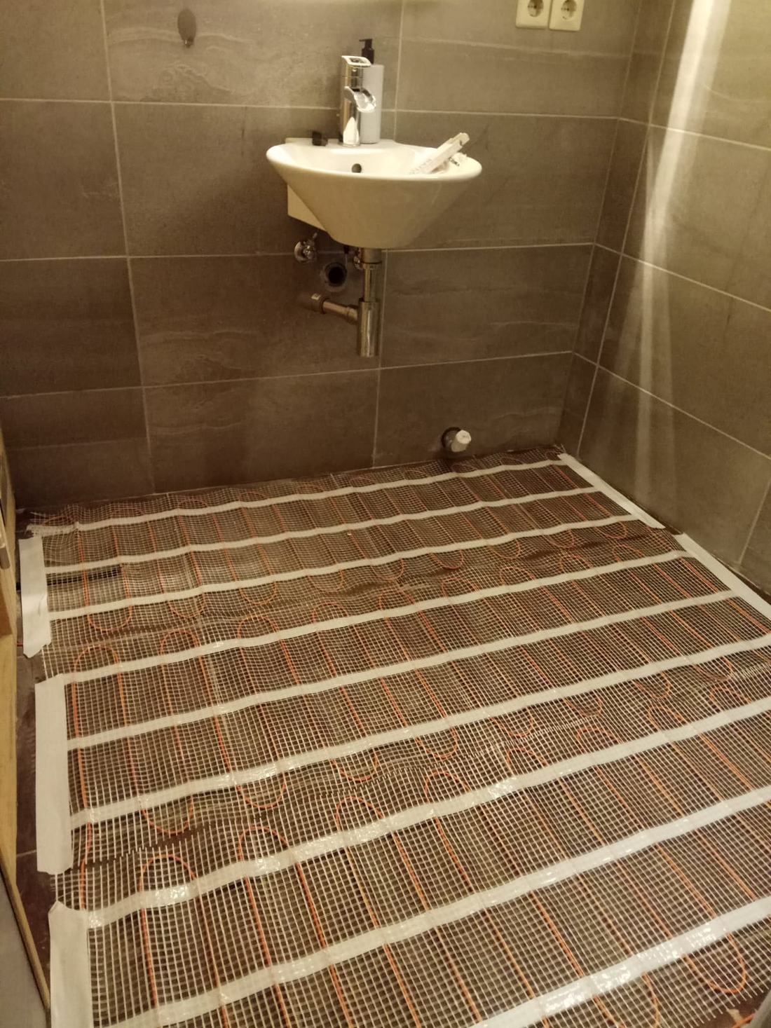 Nattes chauffantes électriques posées sur le sol d'une salle de bain