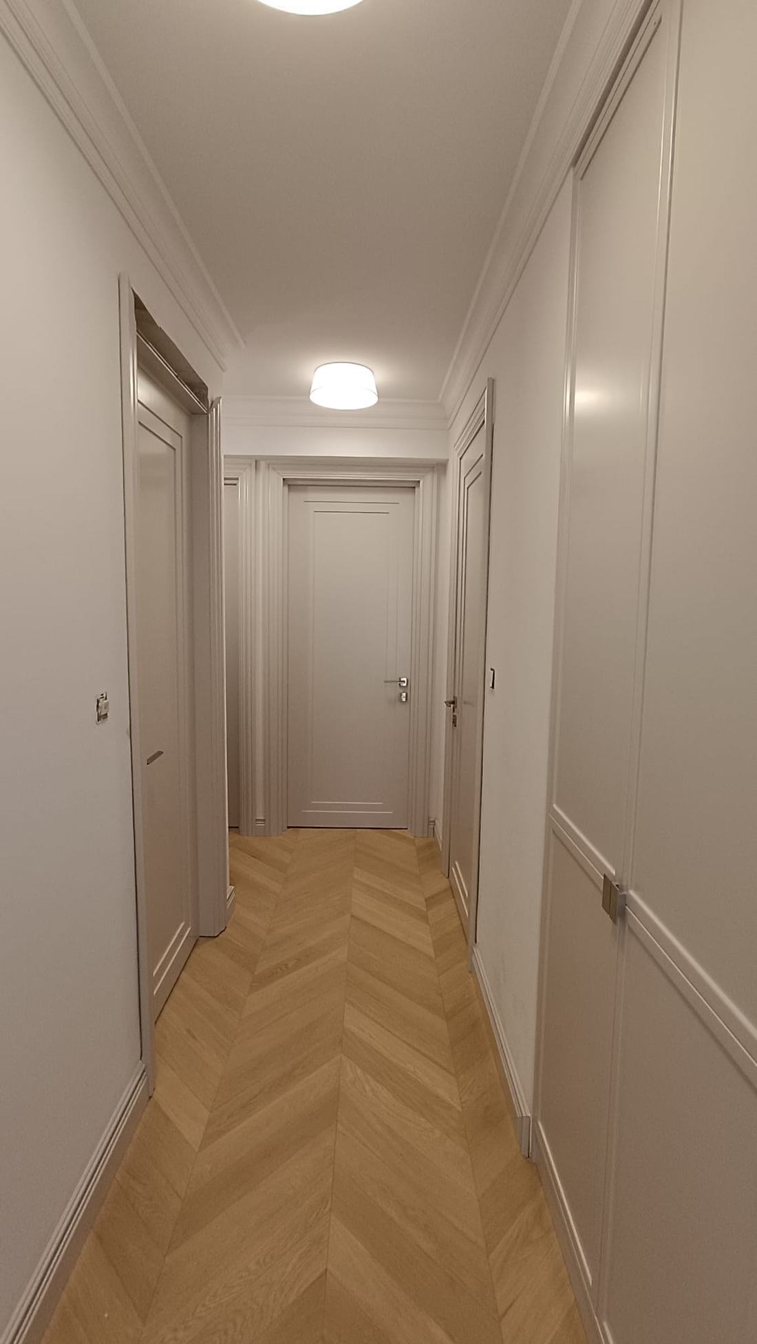 Couloir avec moulures murales, plinthes hautes et parquet à chevrons