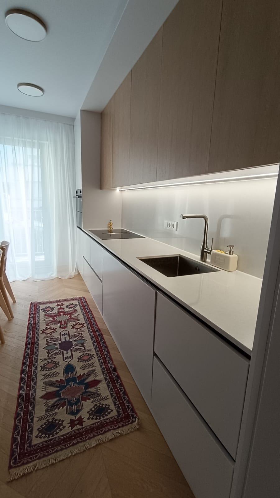 Cuisine blanche aux façades chêne, plan de travail clair et parquet à chevrons