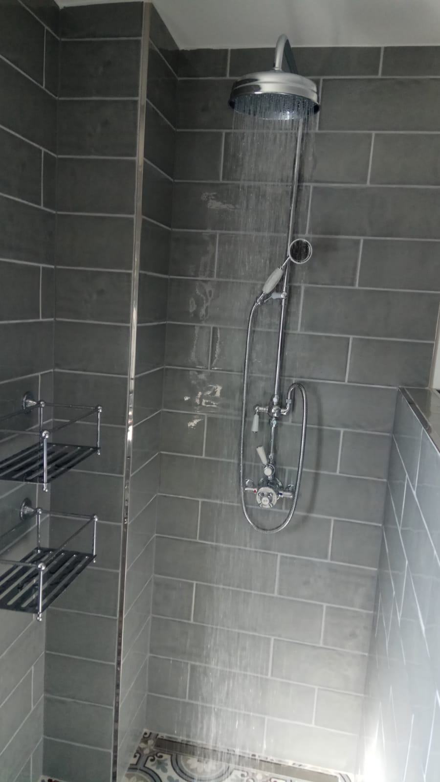 Douche carrelée en gris avec colonne de douche, sol en carreaux de ciment