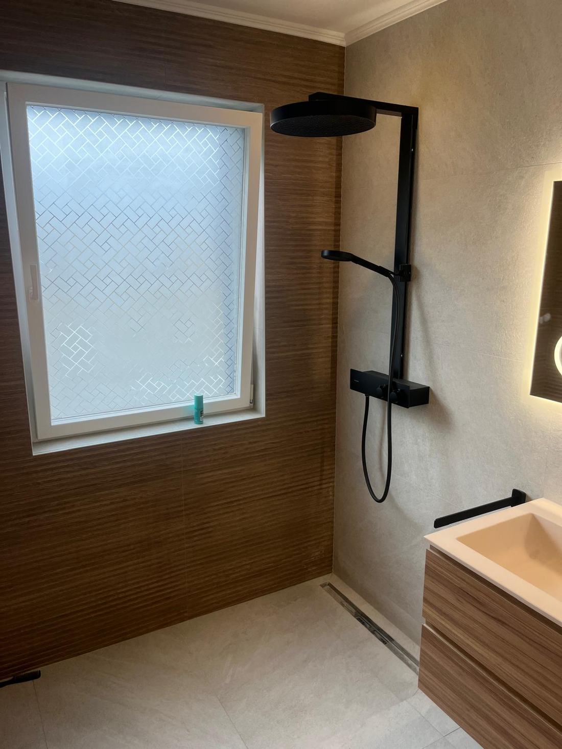 Douche à l'italienne avec colonne noire, mur effet bois et meuble vasque