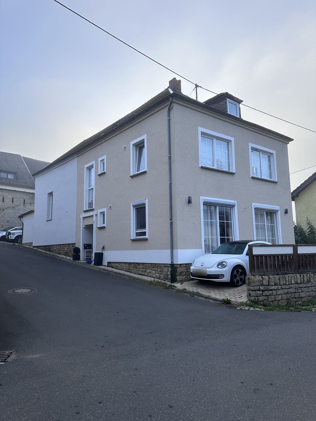 Maison de ville à la façade enduite, avec encadrements de fenêtres blancs et soubassement en pierre