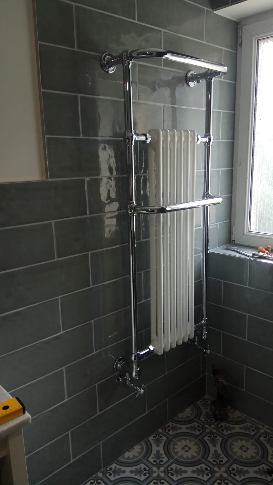Radiateur sèche-serviettes chromé dans une salle de bain carrelée