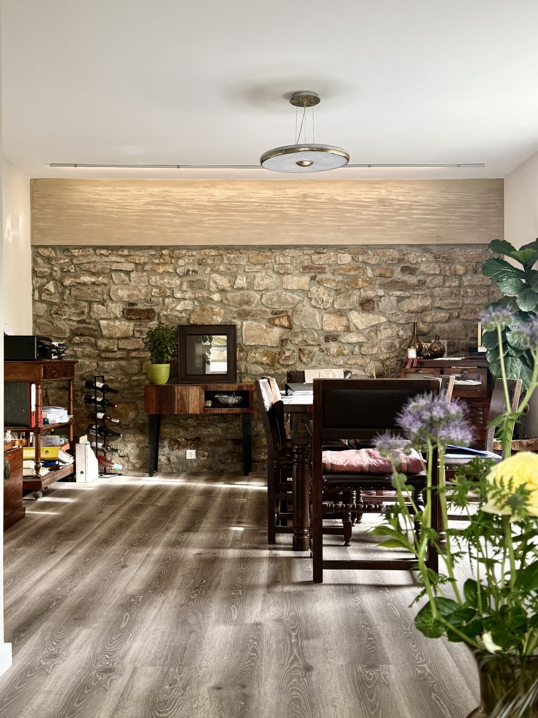 Séjour avec mur en pierres apparentes, éclairage LED en corniche et parquet gris