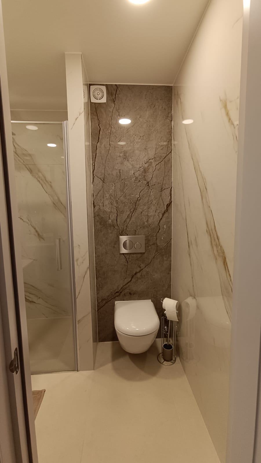 WC suspendu devant un mur effet marbre, réservoir encastré